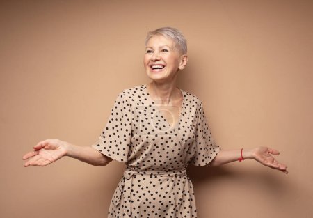 Foto de Hermosa anciana con un corte de pelo corto pixie en un vestido de lunares. Delicia y felicidad. - Imagen libre de derechos