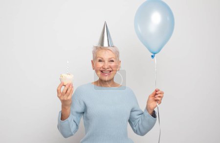 Photo for People, party, aging and maturity concept. Beauitful elderly female wearing conical hat celebrating birthday - Royalty Free Image