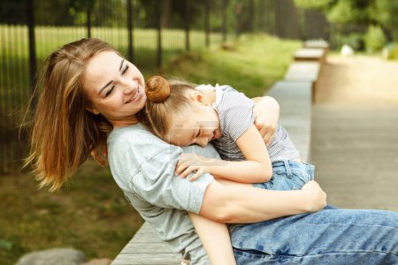Photo for Little daughter hugging her young happy mom in the park. Lifestyle concept. - Royalty Free Image