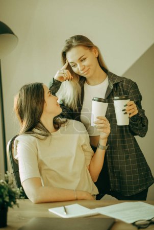 Téléchargez les photos : Deux jeunes femmes boivent du café au bureau et discutent du travail. Concept d'entreprise et de personne. - en image libre de droit