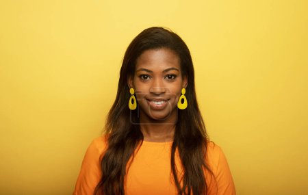 Téléchargez les photos : Charme afro américaine femme sourit happilye sur fond jaune, concept de style de vie - en image libre de droit