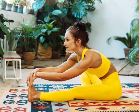 Téléchargez les photos : Une femme brune pratique le yoga dans la jungle urbaine. Femme en yoga asanas et Pilates à la maison. - en image libre de droit