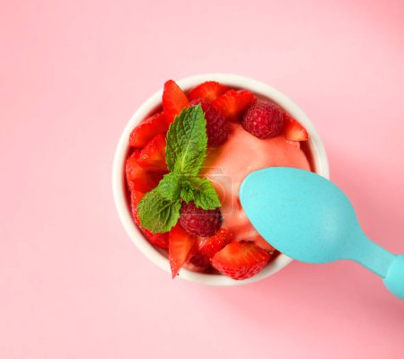 Photo for Strawberry ice cream and blue spoon over pink background, top view - Royalty Free Image