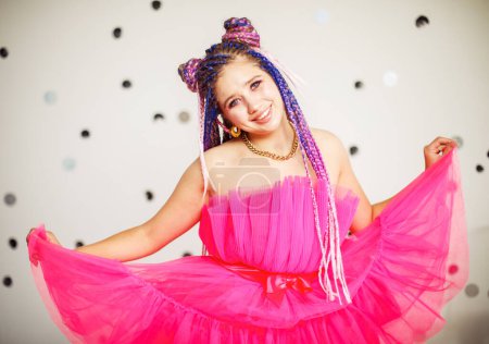Téléchargez les photos : Caucasienne jeune jolie femme avec dreadlocks coiffure portant robe rose, style poupée, maquillage lumineux - en image libre de droit