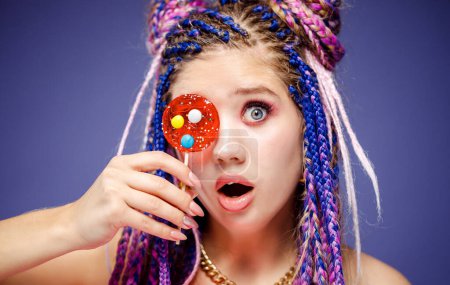 Téléchargez les photos : Jeune jolie femme avec dreadlocks coiffure et maquillage créatif dans le style poupée avec des bonbons - en image libre de droit