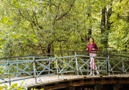 Téléchargez les photos : Jeune femme sportive qui court sur le pont dans le parc d'automne. Concept de mode de vie sain. - en image libre de droit