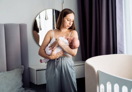 Téléchargez les photos : Maman aimante portant son nouveau-né à la maison. Style de vie et concept de personnes. - en image libre de droit