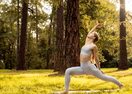Téléchargez les photos : Jeune femme faisant du yoga dans le parc du matin. Sport, santé et yoga concept. Heure d "été. - en image libre de droit