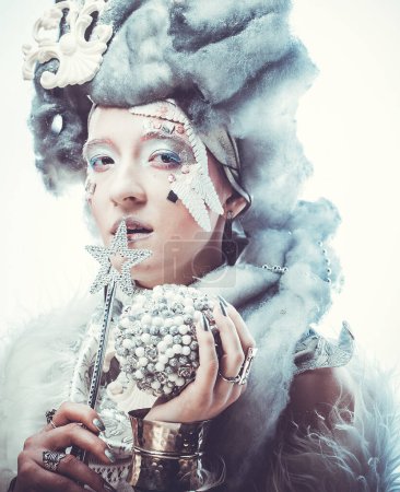 Foto de Retrato de Winter Beauty Woman con peluca plateada sosteniendo varita mágica y bola de Navidad. Hermosa modelo de moda femenina con estilo de pelo de nieve y maquillaje. Reina de invierno. Mujer de Navidad. - Imagen libre de derechos