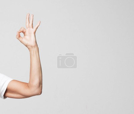 Foto de Vista lateral de la palma de la mano femenina con manicura neutra, mostrar ok, aislado sobre fondo gris. Primer plano detallado plano del estudio. - Imagen libre de derechos