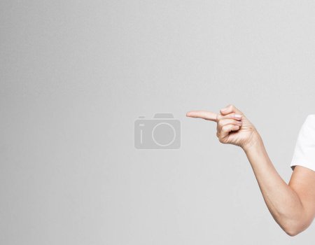 Foto de Mano de una mujer mayor, de cerca, aislada sobre fondo gris. Mujer señala con su dedo, atrayendo la atención. - Imagen libre de derechos
