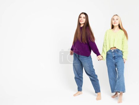 Photo for Studio shot of two young smiling women friends wearing sweaters isolated over white background - Royalty Free Image