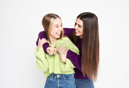 Photo for Studio shot of two young smiling women friends wearing sweaters isolated over white background - Royalty Free Image