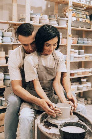 Foto de Pareja joven en el amor trabajando juntos en rueda de alfarero en taller de estudio de artesanía. Concepto de estilo de vida y hobby. - Imagen libre de derechos