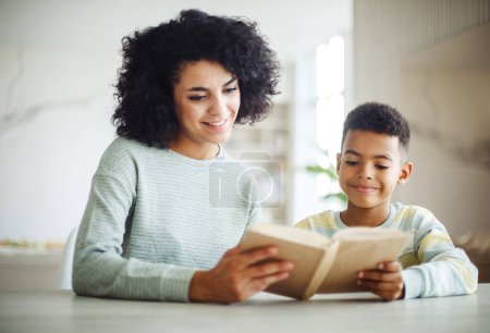 Photo for Portrait of young african american mother hold story book reading teaching little boy in living room. Home school learn from teacher, education happy family. - Royalty Free Image