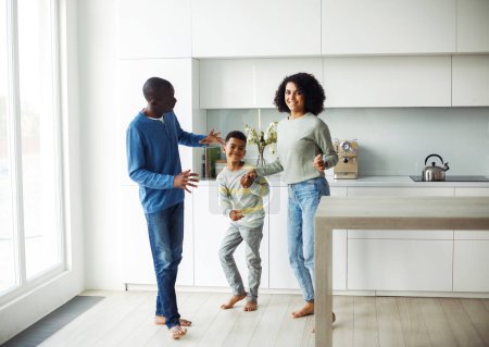 Foto de Alegre familia afroamericana - mamá, papá e hijo bailando en casa. Felices juntos. Estilo de vida y concepto familiar. - Imagen libre de derechos