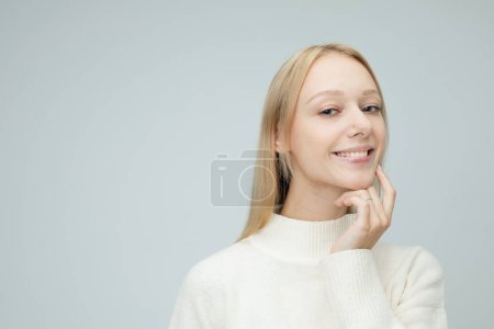 Photo for Lifestyle, emotion and young people concept: young woman dressed casual touches her face over grey background - Royalty Free Image