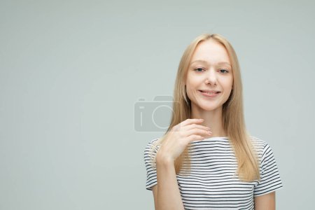 Foto de Alegre joven con el pelo rubio sonriendo aislado sobre fondo de color gris claro - Imagen libre de derechos