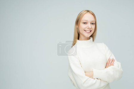 Photo for Young woman with long blond hair dressed casual posing with crossed arms over light grey background - Royalty Free Image