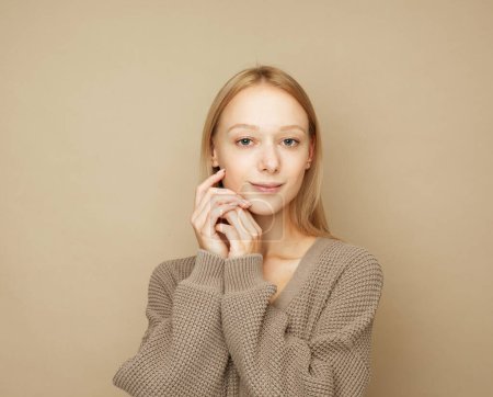 Téléchargez les photos : Style de vie, émotion et concept des jeunes : jeune femme portant un pull marron posant sur fond beige - en image libre de droit