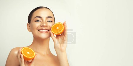 Photo for Portrait of a lovely young woman standing isolated over white background, showing slices of an orange - Royalty Free Image