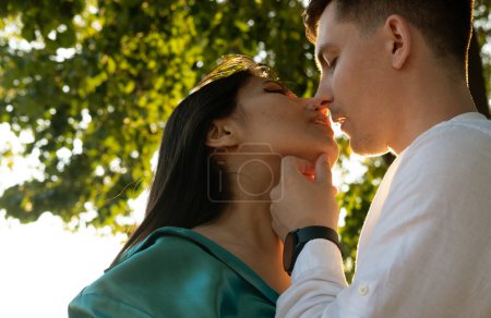 Young happy couple in love of different nationality hugging and kissing in the park. Asian woman and european man.