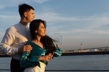 Young couple in love of different nationality hugging near river. Asian woman and european man. Young family.