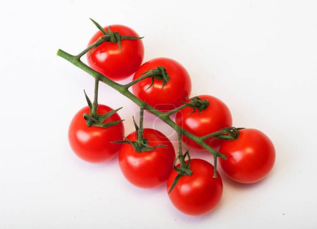 Photo for Red tomatoes on a green twig on white background, close up - Royalty Free Image