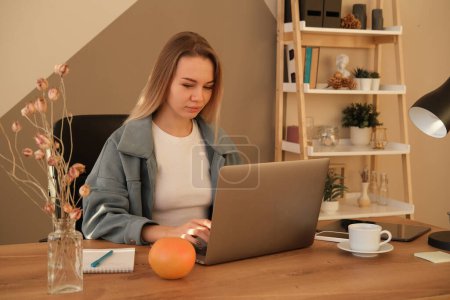 Téléchargez les photos : Jeune femme blonde habillée ordinateur portable de travail occasionnel. Femme d'affaires occupée à travailler sur ordinateur portable au bureau. - en image libre de droit