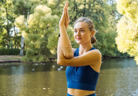 Téléchargez les photos : Portrait d'une jeune femme blonde faisant du yoga dans le jardin pour une séance d'entraînement. Concept de mode de vie fitness et sain. - en image libre de droit