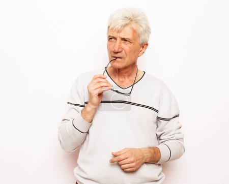 Photo for Old age, problem and people concept: Portrait of thoughtful old man wearing sweater and glasses over white background - Royalty Free Image