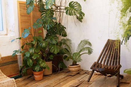 Foto de Cómoda silla de madera sobre suelo de madera junto a flores tropicales. Sala de meditación y relajación. - Imagen libre de derechos