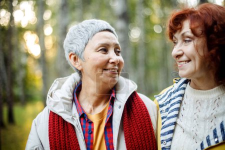 Fröhliche Rentnerinnen plaudern und lachen im herbstlichen Park. Lebensstil und Freundschaftskonzept.