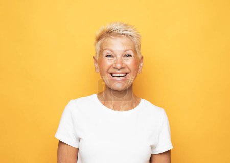 Photo for Lifestyle, emotion and old people concept: Portrait of blond optimistic old lady over yellow background - Royalty Free Image
