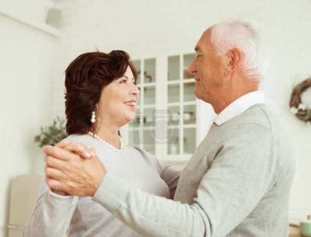 Foto de Una hermosa pareja de ancianos casados está bailando en la habitación. Los pensionistas son felices juntos. Feliz vejez. - Imagen libre de derechos