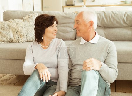 Téléchargez les photos : Un couple âgé serrant dans ses bras alors qu'il était assis sur le sol du salon. Relation, personnes et concept familial. - en image libre de droit