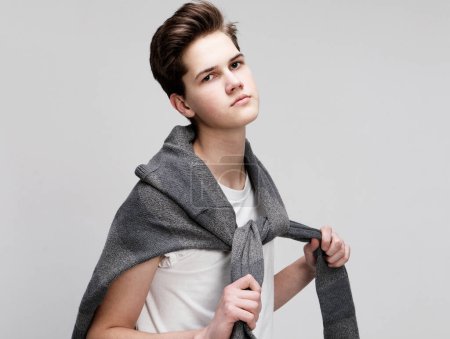 Foto de Joven guapo adolescente hipster chico usando suéter posando sobre blanco fondo aislado - Imagen libre de derechos