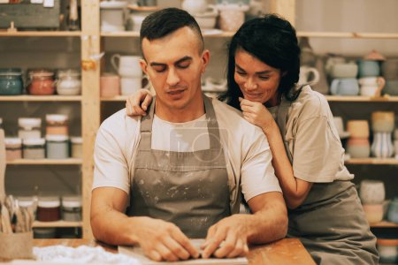 Téléchargez les photos : Un jeune couple souriant est engagé dans la créativité dans un atelier de poterie - en image libre de droit