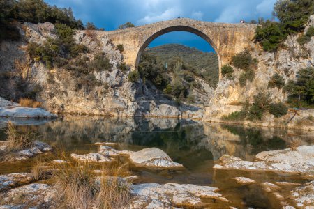 Foto de Vista de un antiguo puente Pont de Llierca en Cataluña, España. Este hermoso puente, pavimentado con losas de arenisca, está en uso desde el siglo XIV. - Imagen libre de derechos