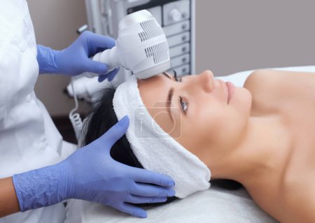 Téléchargez les photos : Le médecin-cosmétologue effectue la procédure Cryothérapie de la peau du visage d'une belle jeune femme dans un salon de beauté.
. - en image libre de droit