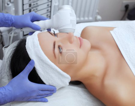 Photo for The doctor-cosmetologist makes the procedure Cryotherapy of the facial skin of a beautiful, young woman in a beauty salon.Cosmetology and professional skin care. - Royalty Free Image