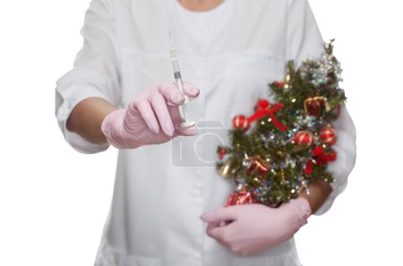 Téléchargez les photos : Le cosmétologue médical tient une seringue injectable et un petit sapin de Noël décoré dans le salon de beauté. Soins cosmétiques pour la peau. - en image libre de droit