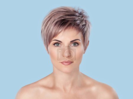 Portrait of a beautiful blonde woman with beautiful make-up and short haircut after dyeing hair in a hairdressing salon on a pink background.
