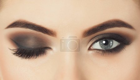 Photo for Beautiful woman with long eyelashes and with beautiful evening make-up. Eyes close up.One eye is closed and the other is open. - Royalty Free Image