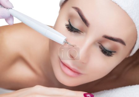 Téléchargez les photos : Le cosmétologue fait la procédure de traitement de Couperose de la peau du visage d'une belle, jeune femme dans un salon de beauté.. - en image libre de droit