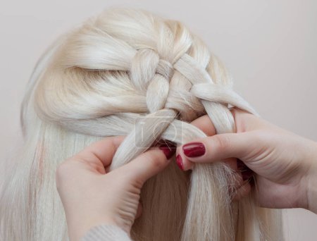 Photo for Beautiful girl with blonde hair, hairdresser weaves a  braid close-up, in a beauty salon. Professional hair care and creating hairstyles. - Royalty Free Image