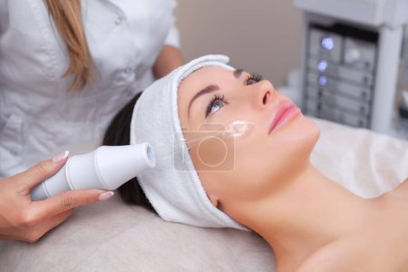 Photo for The doctor-cosmetologist makes the procedure Microcurrent therapy On the hair of a beautiful, young woman in a beauty salon.Cosmetology and professional skin care. - Royalty Free Image