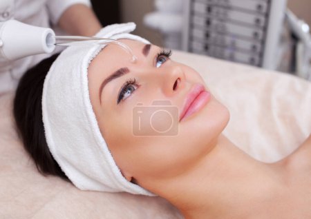 Photo for The cosmetologist makes the procedure electrotherapy  of the facial skin of a beautiful, young woman in a beauty salon.Cosmetology and professional skin care. - Royalty Free Image