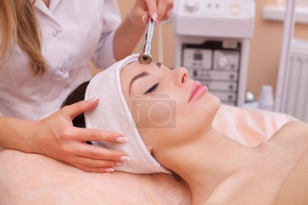 Photo for The doctor-cosmetologist makes the procedure Microdermabrasion of the facial skin of a beautiful, young woman in a beauty salon.Cosmetology and professional skin care. - Royalty Free Image