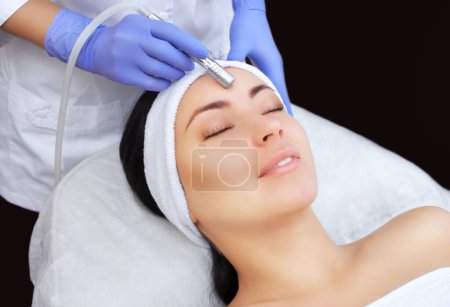 Photo for The cosmetologist makes the procedure Microdermabrasion of the facial skin of a beautiful, young woman in a beauty salon.Cosmetology and professional skin care. - Royalty Free Image